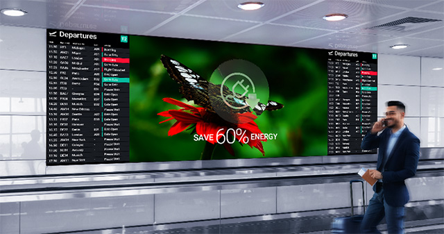 A man walks by a large digital display showing flight information